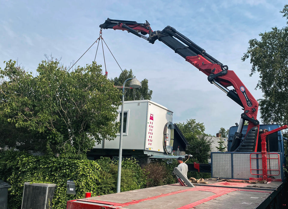 En beboelsesvogn bliver løftet over hækken på en villavej