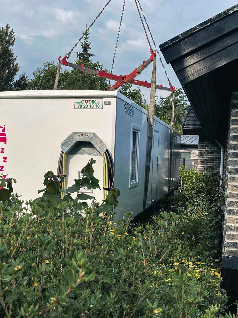 En beboelsesvogn bliver placeret i haven ved et parcelhus